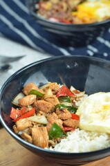 Ricebowl with egg and chicken filet served in bowl on the table