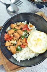 Ricebowl with egg and chicken filet served in bowl on the table