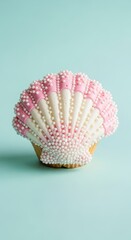 Seashell shaped cupcake with pink and white frosting and sprinkles