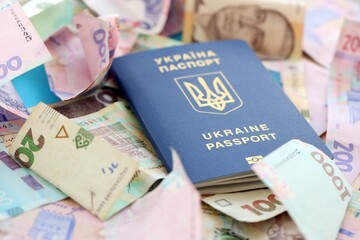 Ukrainian biometrical passport lies on big amount of different ukrainian hryvnia money bills
