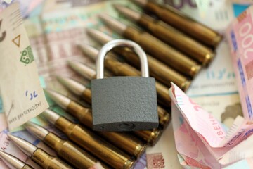 Big amount of different Ukrainian hryvnia money bills and bullets with padlock