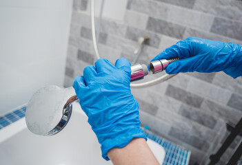 Woman's hands in gloves connecting the hose to a shower head