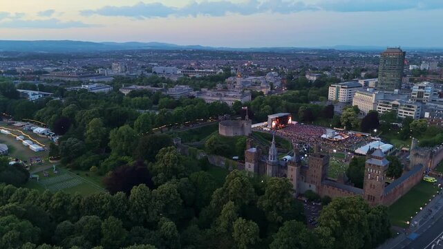 Aerial drone footage of Cardiff city centre at night with an electronic music gig taking place at the castle grounds. Panning shot from right to left towards Bute Park.