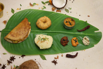 South indian thali food with sambhar and different types of chutney served on banana leaf