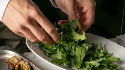 Chef's hands dance over vibrant arugula, evoking flavors of Festive Herb Day, culinary artistry in...