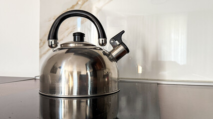 A sleek stainless steel kettle reflects morning light, evoking Hygge comfort and International Tea...