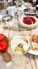 White wine glass glistens amid vibrant cherry-tomato chaos, hinting at a secret midsummer feast of forgotten culinary delights
