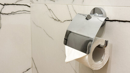 Sleek chrome toilet paper holder glistens in minimalist marble sanctuary, evoking Hygge tranquility...