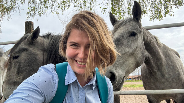Smiling woman with playful horses, equine joy on St Stephen's Day, celebrating harmony with nature and rural serenity