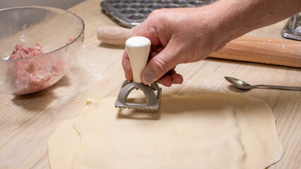 Crafting rustic dumplings with a handheld stamp, a European man's hands prepare for Lunar New Year...