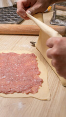 Rolling fresh pasta dough with hearty filling, culinary artistry for Italian Nonna's Day, evokes warmth and tradition