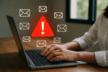 Person working on a laptop with email alert icons.