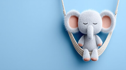 Soft, plush elephant toy swinging against a blue background, evoking a playful and whimsical atmosphere.