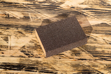 sandpaper on sponge for manual polishing of wooden surfaces, wooden board made of pine planks for...