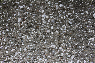 Close up of gravel aggregate concrete wall background. Rough surface of pebbles embedded grey wall texture.