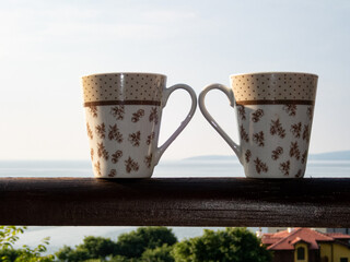 Two cups on wooden handrail