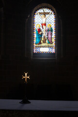 Sun shining through a church stained glass within on a cross