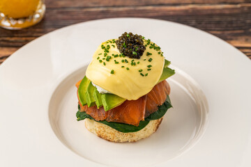 Gourmet eggs benedict with smoked salmon and caviar on white plate