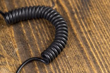 a black cable twisted in the shape of a spring for equipment close up, an old black cable in a rubber braid for connecting different devices