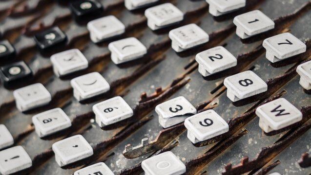 A close up of an old typewriter keyboard with white keys and black letters and numbers visible on them