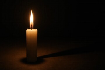 A solitary candle flickers in the darkness, casting a warm glow on its surroundings