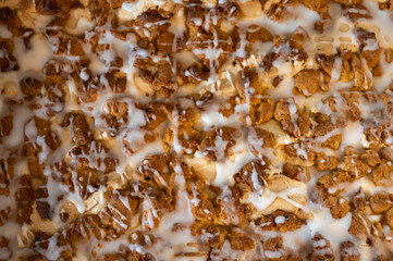 Close-up of freshly baked crumb cake with golden brown streusel topping and white icing drizzle, homemade dessert in warm lighting.