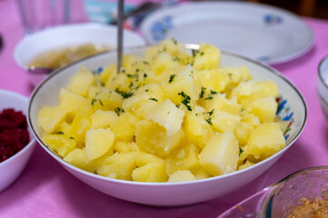 Bowl of fluffy boiled potatoes garnished with fresh chopped parsley, served as a warm side dish for a hearty meal.