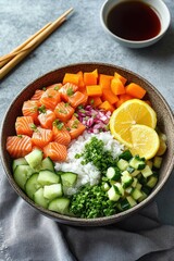 Fresh salmon poke bowl with diced carrots, cucumber slices, chopped green onions, rice, lemon slices, and soy sauce on the side with chopsticks