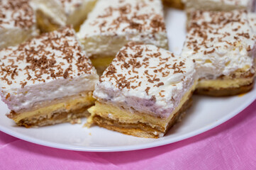 Close-up of homemade layered cake slices with whipped cream topping and grated chocolate, served on...