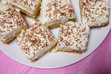 Close-up of homemade layered cake slices with whipped cream topping and grated chocolate, served on...