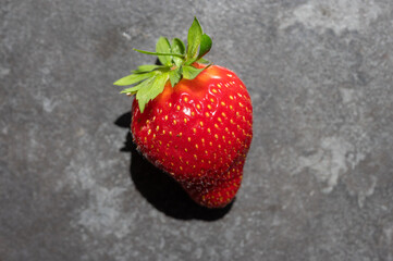 Close-up of a fresh ripe strawberry with detailed texture and seeds, captured in natural light.