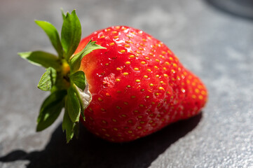 Close-up of a fresh ripe strawberry with detailed texture and seeds, captured in natural light.