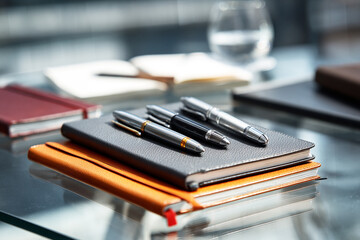 Close-up of notebooks and pens on a glass table writing stationery