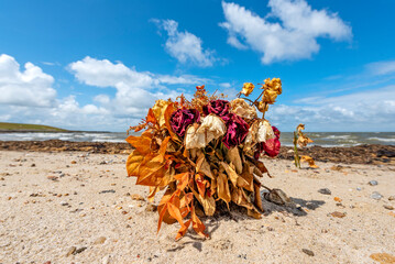 Verwelkter, am Strand der Nordseeküste aufgestellter, oder angespülter Blumenstrauß, evtl. als...