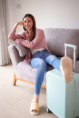 Obraz premium Asian adult woman relaxes home sofa with suitcase ready for travel vacation departure journey