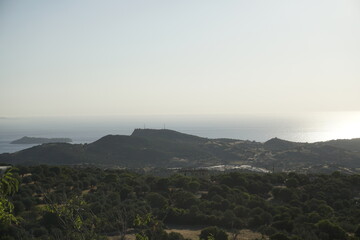 Beautiful view of the sea from a mountain road on a hot summer day. Haze and bright sunlight.