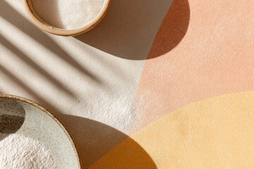 Powdery texture with soft sunlight and abstract shadow on pastel background, minimalistic kitchen scene with ceramic bowls and flour, calm and serene atmosphere for baking inspiration