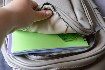 open backpack with school supplies: green notebook, ruler, pen, and highlighter. themes: education, back to school, student life, learning, stationery.