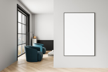Modern interior with blank poster frame on clean wall beside stylish seating area and large window...