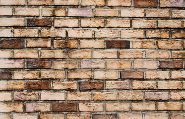 Close-up of a weathered brick wall with varied brown and tan bricks