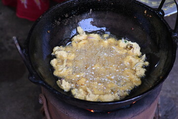 Onion pakora frying in iron pen. This is a popular street food in Indian subcontinent. Onion which are coated in seasoned spicy gram flour batter and deep fried. It originated in India.