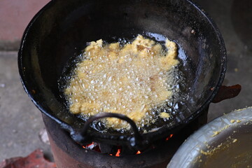 Onion pakora frying in iron pen. This is a popular street food in Indian subcontinent. Onion which are coated in seasoned spicy gram flour batter and deep fried. It originated in India.