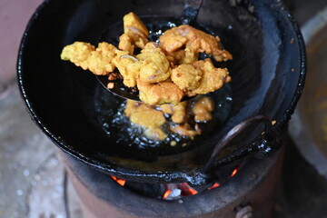 Onion pakora frying in iron pen. This is a popular street food in Indian subcontinent. Onion which...