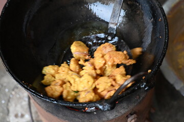 Onion pakora frying in iron pen. This is a popular street food in Indian subcontinent. Onion which...