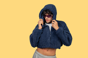 Young latin man wearing sunglasses and blue furry jacket is pulling up his hood