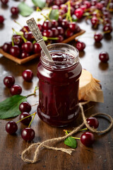 Cherry jam and fresh berries on an old wooden table.