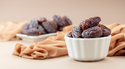 Dates in white dish on a beige background.
