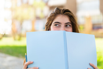 Fototapeta premium Young pretty caucasian woman holding a notebook