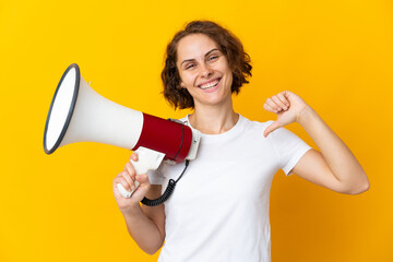 Young English woman isolated on yellow background holding a megaphone and proud and self-satisfied