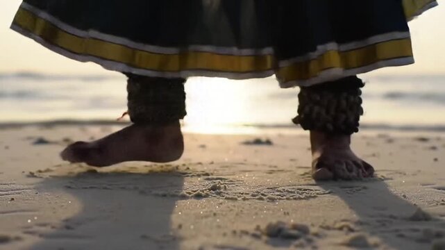 A dancer's feet adorned with anklets move gracefully on a sandy beach, bathed in the warm glow of the setting sun, creating a serene scene.